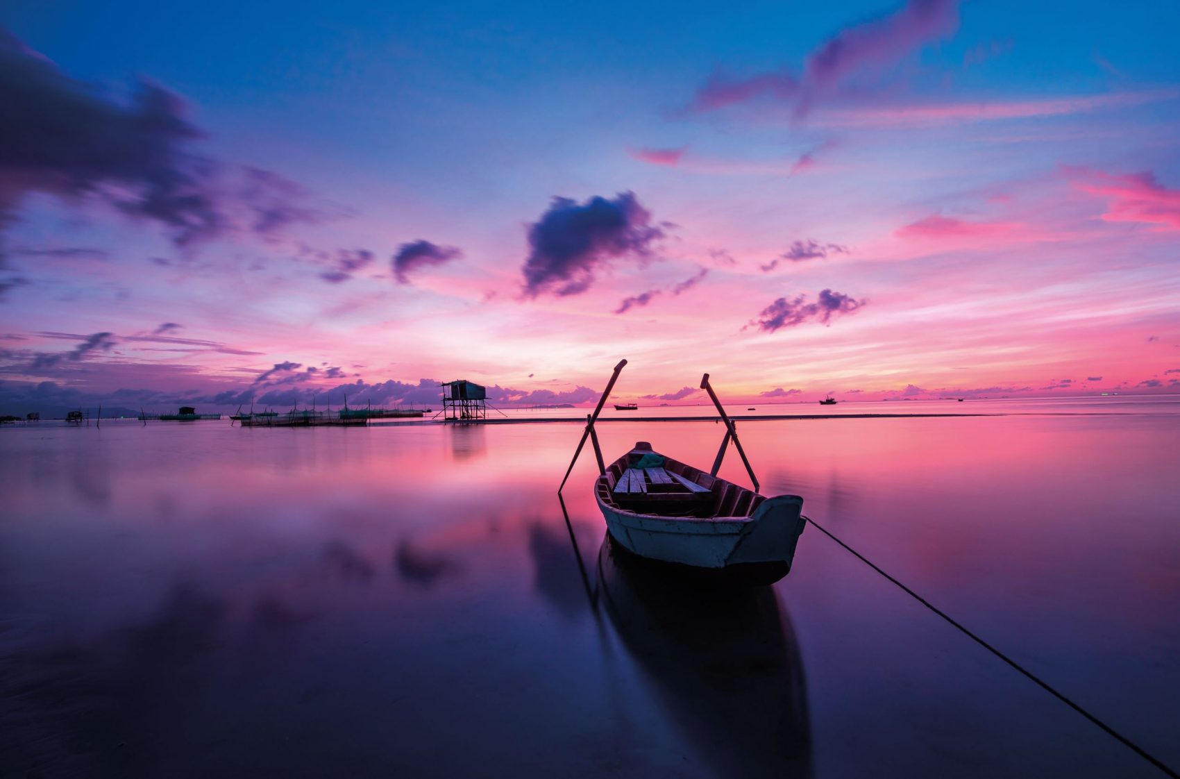 Vene peilityynessä vedessä violetissa valossa auringonnousun aikaan